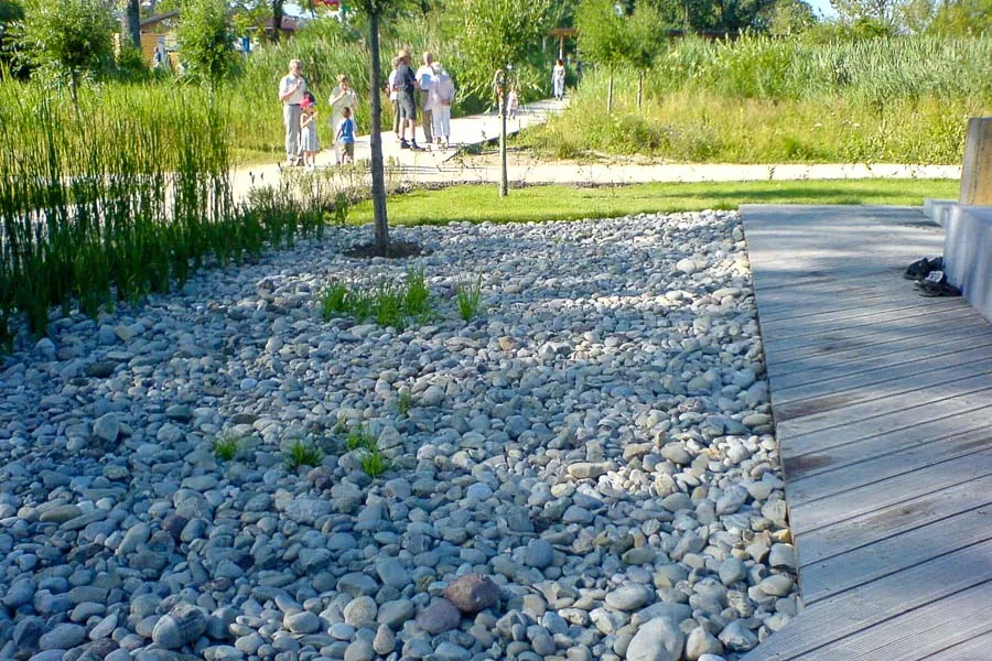 Gartenteich mit Holzsteg, Natursteinmauer und Staudenbepflanzung